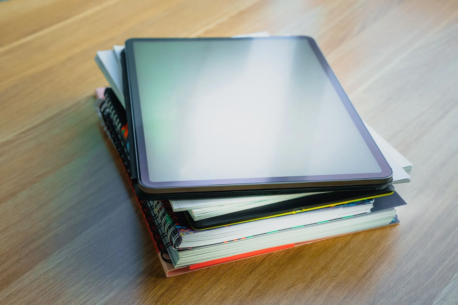 A tablet resting on a stack of books, representing digital products