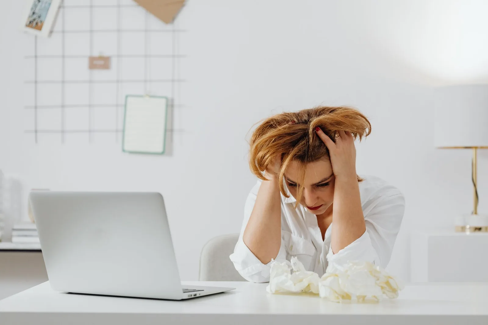 A creator sitting at a laptop with her head in her hands
