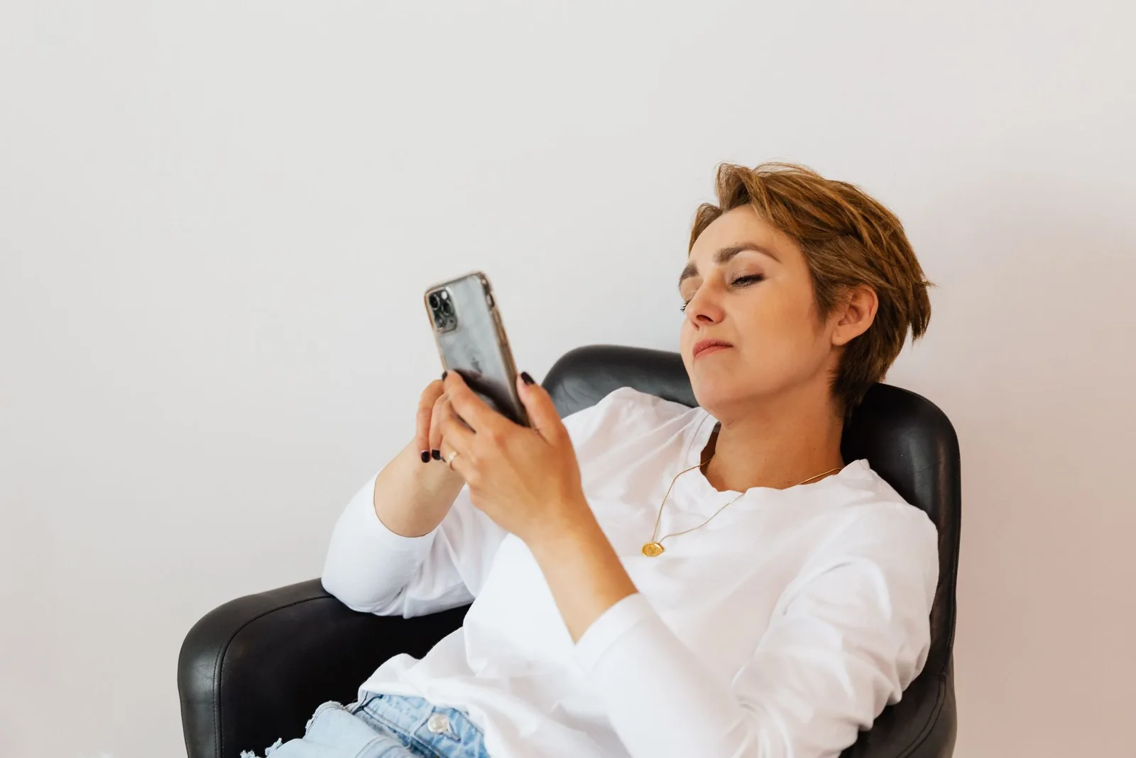 A creator sitting with a phone, looking tired while going through messages