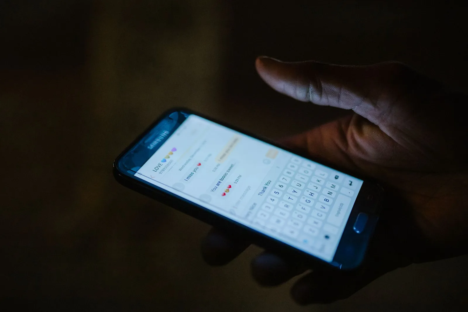 A phone in a dark room showing an open direct message conversation
