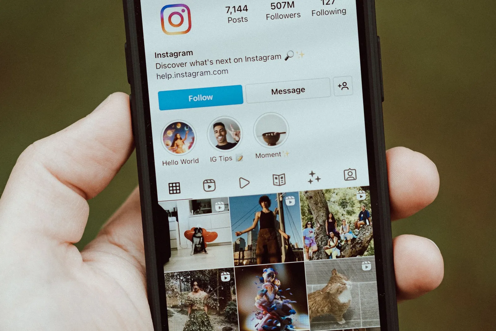 A hand holding a phone showing an Instagram profile