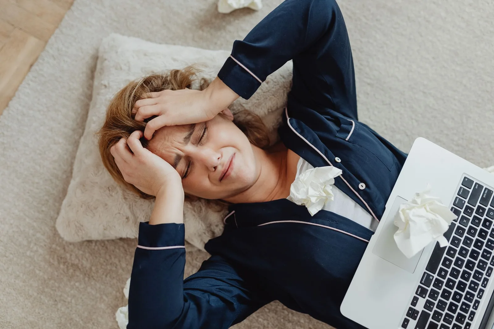 A creator lying on the floor with a laptop looking stuck and frustrated