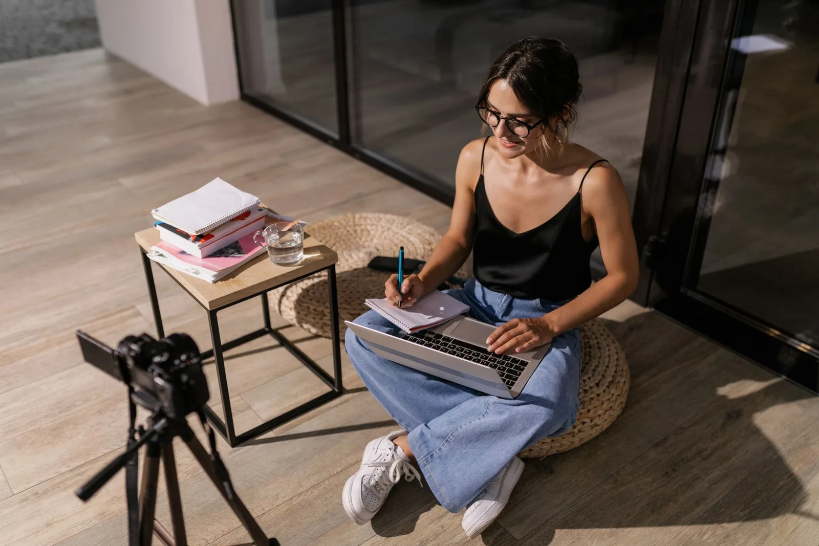 A creator recording an online course lesson at a desk with a laptop and camera