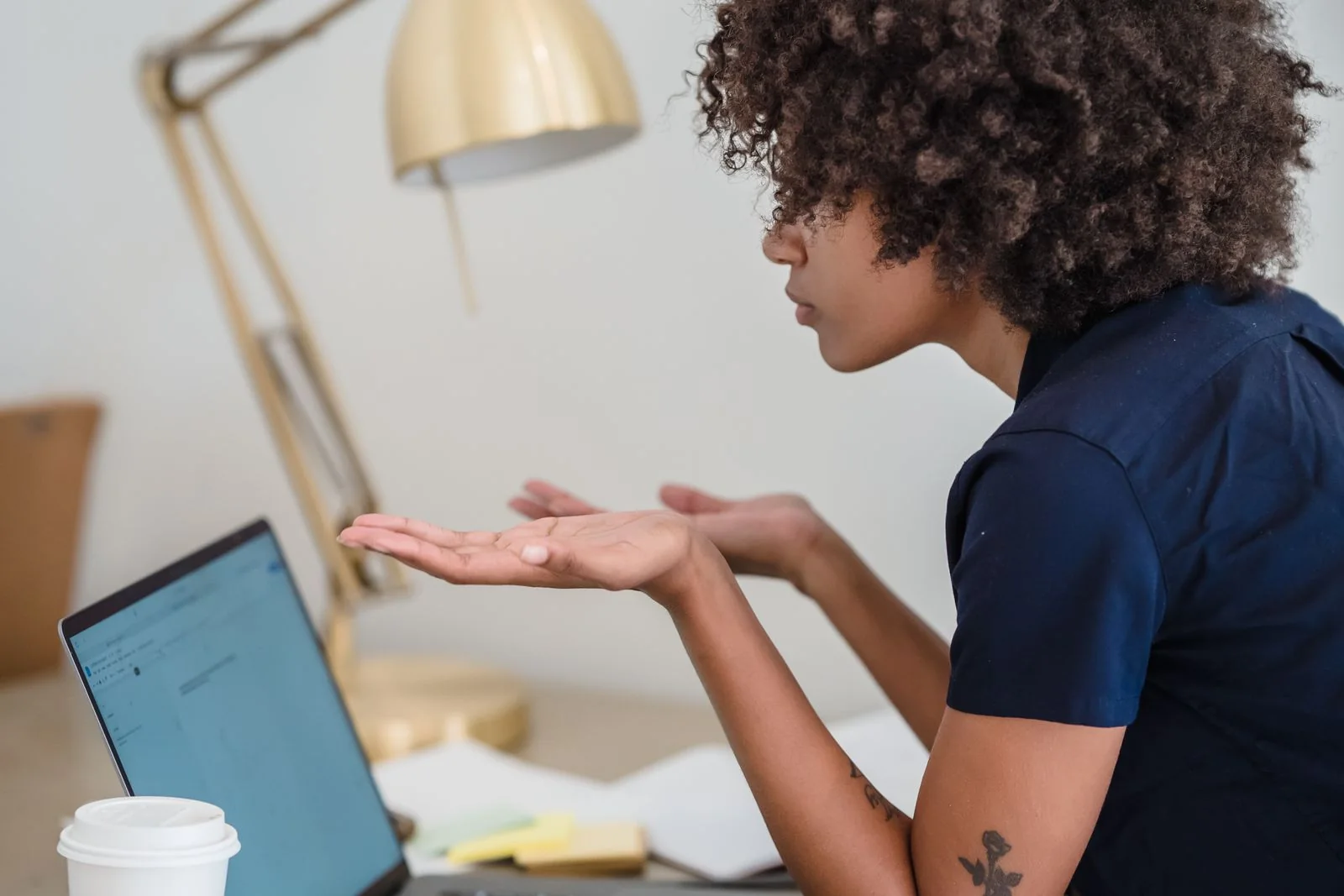A creator at a desk looking at a laptop with her hands raised, unsure what to do next
