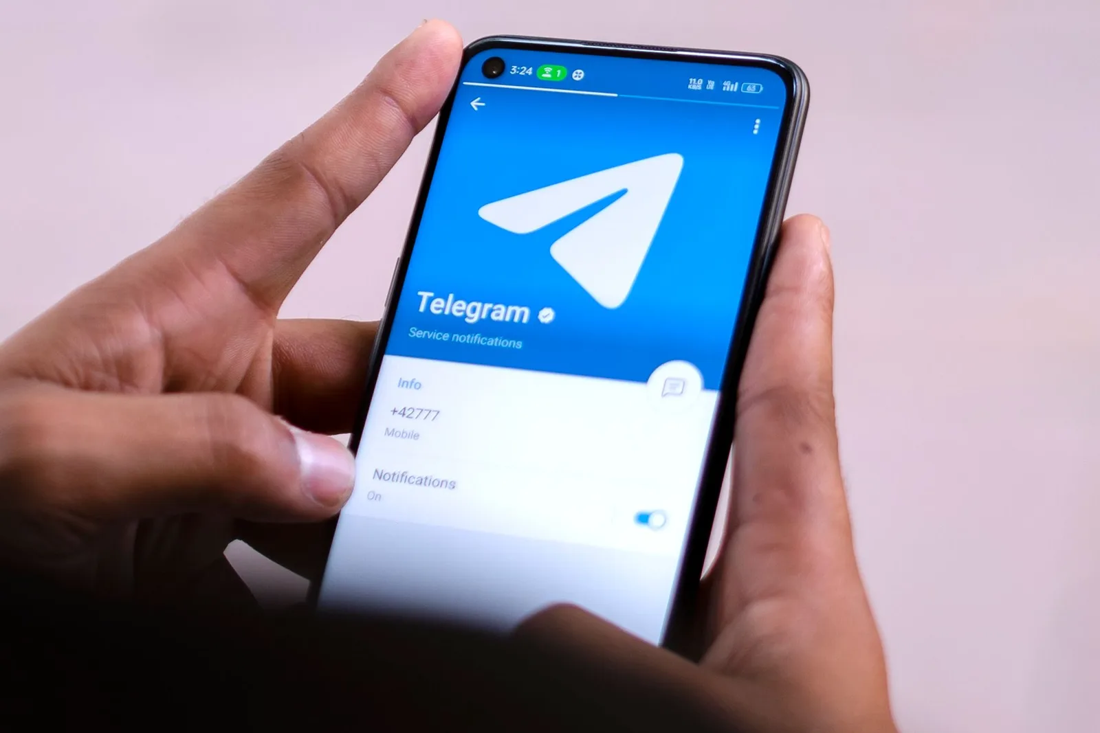 Hands holding a smartphone with the Telegram app open on screen